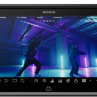 ATOMOS SHOGUN 7-tuumainen HDR-monitori-tallennin 6K RAW näyttää kaksi tanssijaa teollisuusmaisemassa, jossa siniset ja violetit neonvalot, pilarit ja kameran asetukset näkyvät näytön yläreunassa.