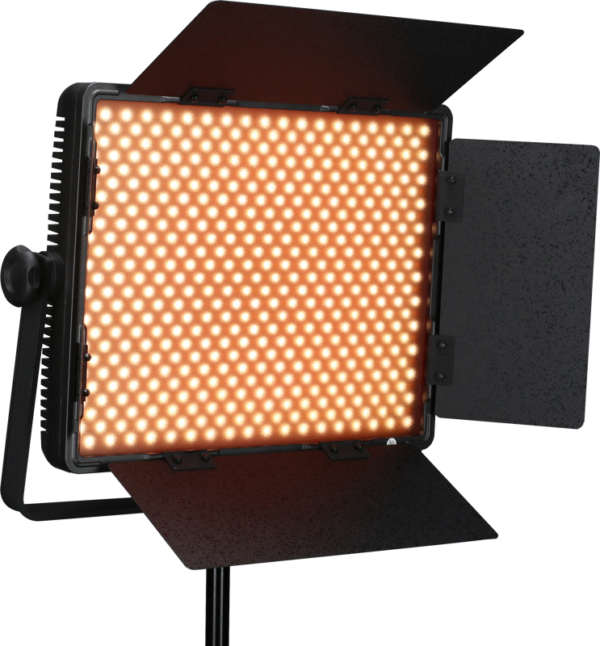 NANLITE 900CSA Bicolor LED-paneeli, jossa on neljä säädettävää mustaa lato-ovea ja joka on asennettu jalustalle, näytetään kytkettynä päälle ja heittää lämmintä oranssia hehkua.