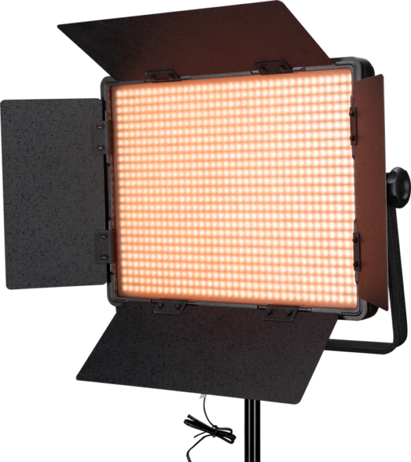 NANLITE 900DSA 5600K LED-paneeli DMX-ohjauksella on suorakulmainen LED-studiovalo, jossa on avoimet lato-ovet ja joka säteilee lämmintä oranssia hehkua. Se on asennettu mustaan jalustaan, jonka alla roikkuu virtajohto.
