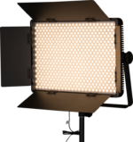 NANLITE 1200CSA Bicolor LED Panel on suorakulmainen studiovalaisin, jossa on lato-ovet ja joka on asennettu jalustalle. Siinä on useita pieniä LED-lamppuja, jotka on järjestetty ruudukkoon, ja siinä on virta päällä.