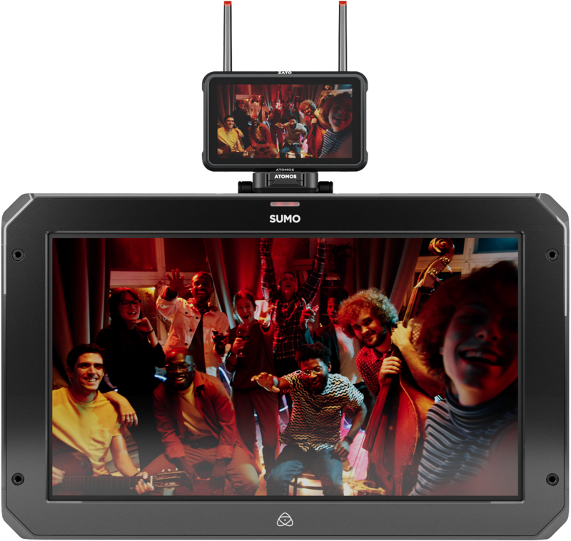 800q-03_125019 The small ATOMOS Z-Mount monitor sits on top of the larger screen, and both show a happy crowd of people posing and smiling in a warmly lit room, some holding musical instruments.