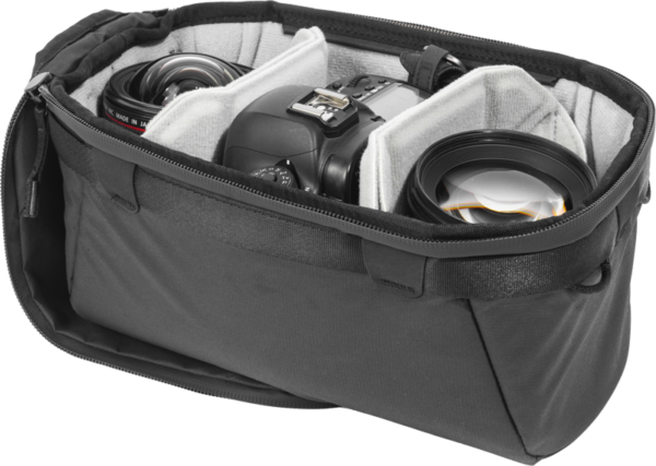 Mustan värinen Peak Design Camera Cube V2 (Small) on avattu, ja sen pehmustettuihin lokeroihin on kiinnitetty siististi DSLR-kamera ja kaksi objektiivia.