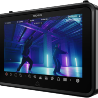 ATOMOS SHOGUN 7-tuumainen HDR-monitori-tallennin 6K RAW näyttää kaksi ihmistä tanssimassa hämärästi valaistussa teollisessa tilassa, jossa on violetteja ja sinisiä neonvaloja, ja kameran ja tallennusliittymän kuvakkeet näkyvät näytöllä.