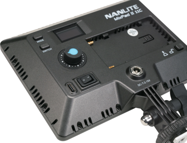 Lähikuva NANLITE MixPad 11C II RGBWW LED-paneelin takapaneelista, jossa näkyvät ohjauspainikkeet, moodivalitsin, kytkin, digitaalinäyttö ja paristolokero. Laite on osittain asennettu tukivarteen.