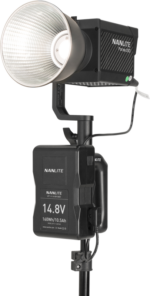 The Nanlite Forza 150 studio LED light is mounted on a stand with a large reflector and a NANLITE V Mount battery handle with a 4-pin XLR connector attached under the light.