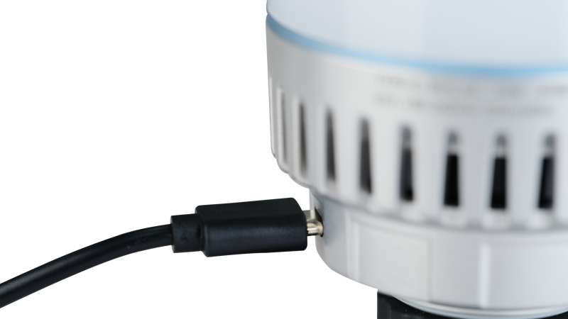 Close-up of a NANLITE USB-C to DMX Cable Splitter connected to a round, white device with ventilation slots on the side against a plain background.