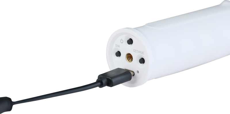Close-up of the NANLITE USB-C to DMX Cable Splitter, a white cylindrical device charged by a black USB cable with control buttons marked DIM and CCT/Mode on one end.