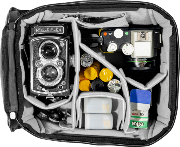 Avoimessa Peak Design Camera Cube V2 (S-Medium) -kamerakuutiossa on Rolleiflex-kaksoiskamera, kompakti filmikamera, filmirullia, kanistereita ja kaksi laatikkoa Erka-väridiafilmiä, jotka on järjestetty siististi pehmustettuihin lokeroihin.