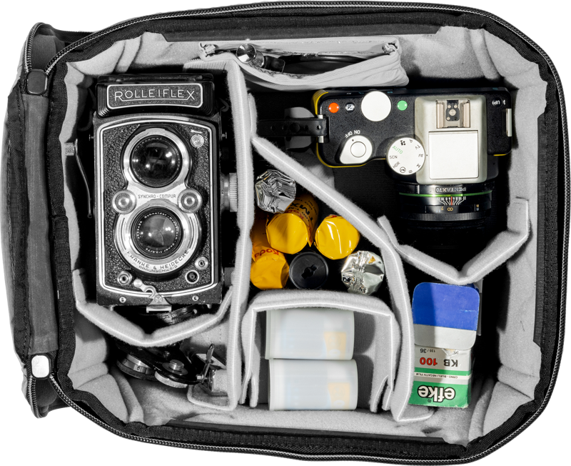 Avoimessa Peak Design Camera Cube V2 (S-Medium) -kamerakuutiossa on Rolleiflex-kaksoiskamera, kompakti filmikamera, filmirullia, kanistereita ja kaksi laatikkoa Erka-väridiafilmiä, jotka on järjestetty siististi pehmustettuihin lokeroihin.