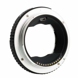 Viltrox EF - GFX II Autofocus Adapterin lähikuvassa sen metallisesta ja mustasta renkaasta paljastuvat elektroniset koskettimet ja USB-portti, jotka mahdollistavat automaattitarkennuksen yhteensopivuuden EF-mount-objektiivien ja Fujifilm GFX -kamerarunkojen välillä.