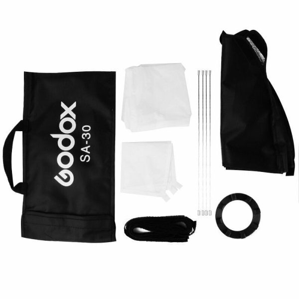 Godox Softbox + Grid 30x30cm -pakkaus sisältää mustan kantolaukun, kaksi valkoista diffuusiokangasta, neljä kaapelisiteitä, taitetun mustan softboxin, hihnan ja pyöreän kiinnitysrenkaan, kaikki valkoisella pohjalla.