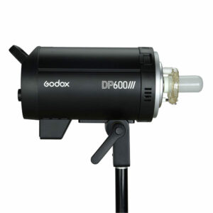 Musta Godox DP600III -studiostrobovalo on asennettu valotelineeseen, ja se näkyy sivulta valkoista taustaa vasten. Laitteessa on näkyvä lamppu ja sen rungossa on sen tuotemerkin etiketti.
