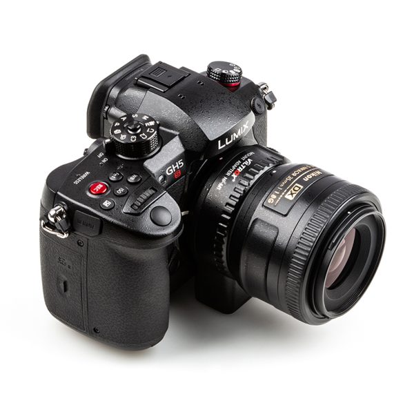 Valkoisella taustalla näkyy musta Panasonic Lumix GH5 -kamera, jossa on erilaisia painikkeita ja valitsimia ja joka on varustettu Viltrox Nikon F-M1 -objektiivin kiinnityssovittimella.