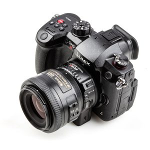 Kuvassa on musta Panasonic Lumix GH5 -kamera, johon on kiinnitetty Viltrox Nikon F - M1 -objektiivin kiinnityssovitin, kuvattuna valkoisella taustalla.