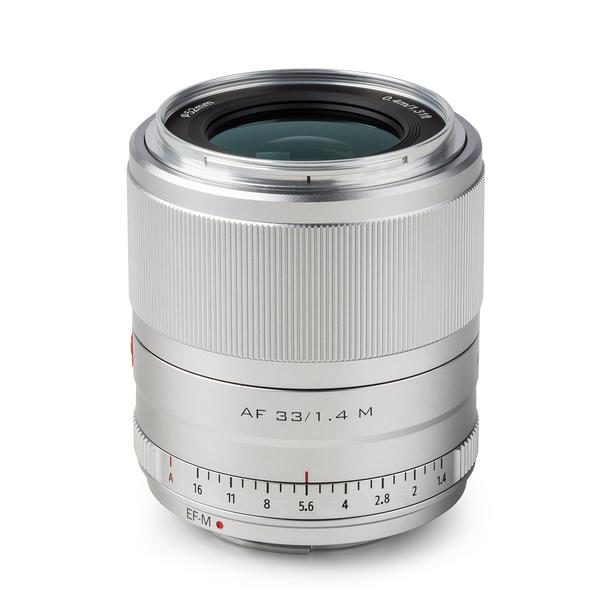 Silver Viltrox AF 33mm f/1.4 lens, Fuji X lens standing upright on a white background, with "AF 33/1.4 M" and "Viltrox" written on it, and with manual focus and aperture rings.