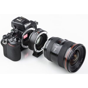 Nikon-kameran runko on liitetty Viltrox EF - Z2 Speed Boosteriin, joka on kiinnitetty suureen kameran objektiiviin, kaikki valkoisella taustalla.