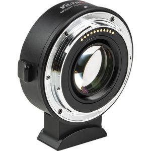 Lähikuva Viltrox EF-Z2 Speed Booster -objektiivin kiinnityssovittimesta, jossa on metallirengas, elektroniset koskettimet ja objektiivielementti, joka seisoo pystyssä pienellä mustalla alustalla valkoista taustaa vasten.