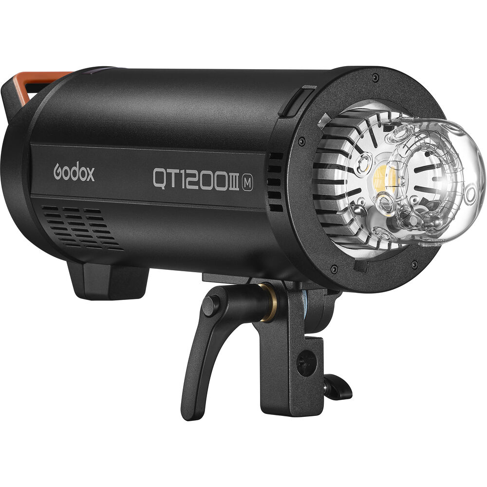 Godox QT1200IIIM on musta studiosalama, jossa on lieriömäinen muotoilu, joka on kiinnitetty kääntyvään kiinnikkeeseen ja jossa on kirkas lasinen salamaputki ja heijastin edessä.