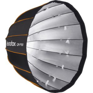 Suuri, pyöreä, musta-hopea Godox Quick Release Parabolic Softbox QR PF90 Profoto, jossa on oranssi reunus ja uurrettu rakenne, joka on suunniteltu hajottamaan valoa valokuvaukseen tai videokuvaukseen.