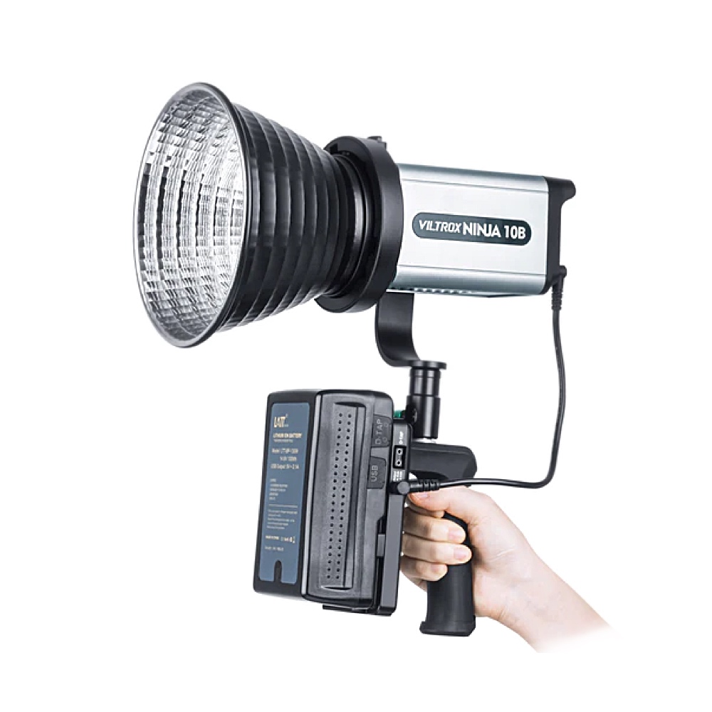Käsi, jossa on Viltrox Ninja10B COB Bi LED -valaisin -LED-valo, jossa on suuri heijastin, kahva ja kiinnitetty akku.