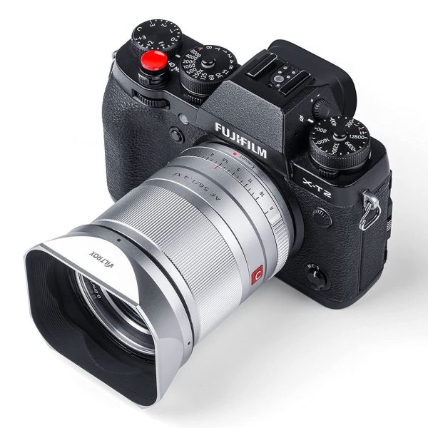 Mustaa Fujifilm X-T2 -digitaalikameraa näytetään ylhäältä päin kulmasta, ja siinä on erilaisia valintakiekkoja ja painikkeita, ja sen objektiiviin on kiinnitetty suuri Viltrox 23/33/56 mm:n metallinen nelikulmainen huppu (hopea).