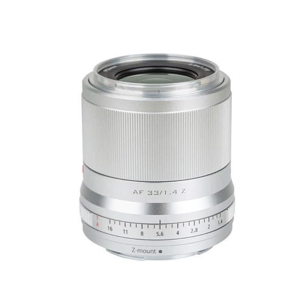 Viltrox AF 33mm f/1.4 -objektiivi Nikon Z:lle, kuvassa hopeanvärinen, jossa on uurrettu tarkennusrengas ja aukkoasteikko (f/1.4-f/16), on kuvattu valkoista taustaa vasten.