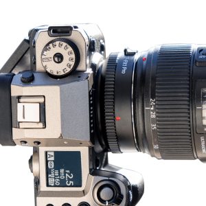 Close-up of a digital camera with Viltrox EF - FX1 PRO Autofocus Adapter, showing controls, buttons and part of the lens barrel with focal length markings visible.
