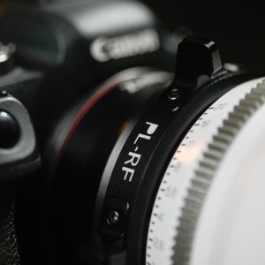 Lähikuva Viltrox PL - RF -sovittimesta kiinnitettynä Canon-kameran runkoon, tarkennusrengas näkyy etualalla.
