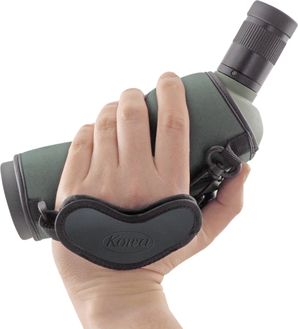 Käsi, joka pitää tähystintä, johon on kiinnitetty KOWA Hand Strap for Spottingscope -käsihihna, jossa on vihreää ja mustaa väriä valkoista taustaa vasten.