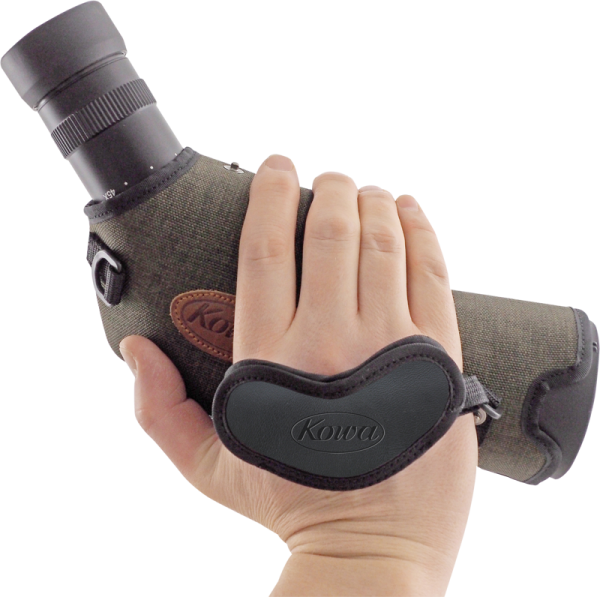 Käsi pitelee vihreää Kowa-kiikaritähtäintä, joka on varustettu mustalla sydämenmuotoisella KOWA Hand Strap for Spottingscope -käsihihnalla, valkoisella taustalla.