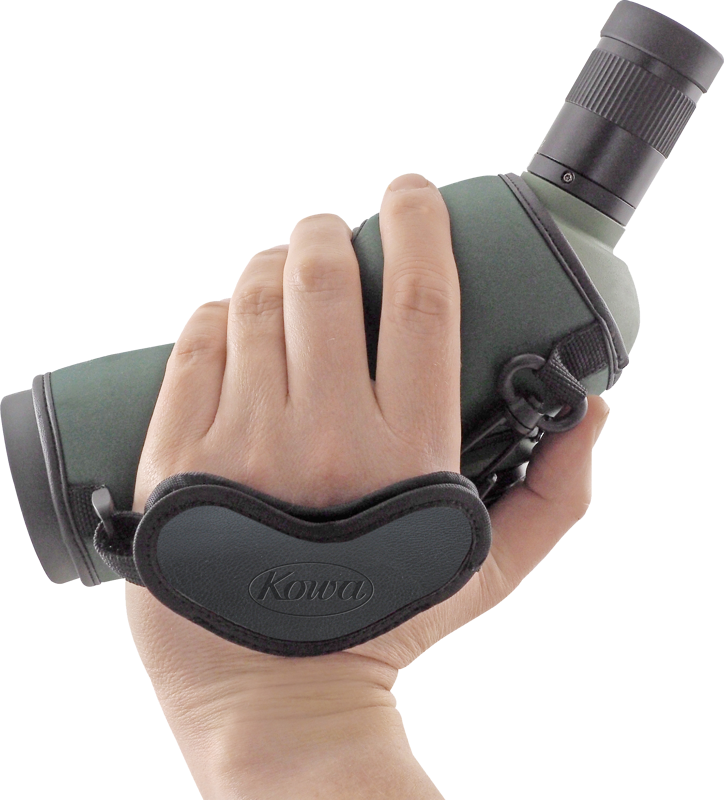Käsi tarttuu tähystyskaukoputkeen, joka on kiinnitetty pehmustetulla, merkityllä KOWA Hand Strap for Spottingscope -käsihihnalla.