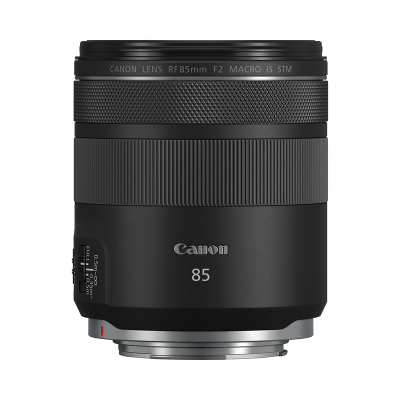 Canon RF 85mm F2 Macro IS STM seisoo pystyasennossa tavallisella valkoisella pohjalla, ja sen säätimet ja tuotemerkki ovat selvästi näkyvissä.