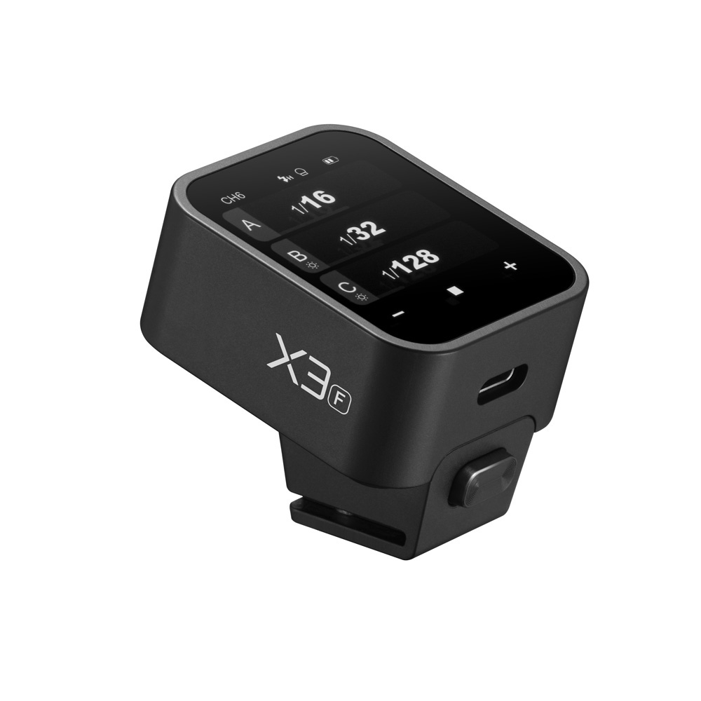 Godox X3 lähetin - Fujifilm on musta elektroninen laite, jossa on digitaalinen näyttö, jossa on merkintä X3 ja jossa on painikkeet ja USB-C-portti, jota todennäköisesti käytetään asetusten ohjaamiseen tai seurantaan.
