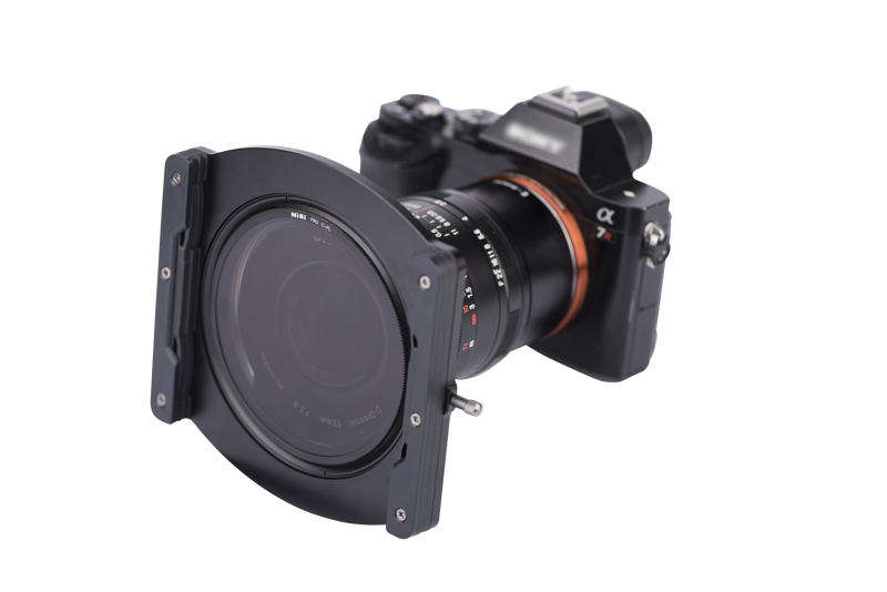 The Nisi Filter Holder for Laowa 12mm f/2.8 is attached to a digital camera lens against a white background.