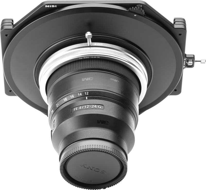 Lähikuva NiSi-suodattimen pidikkeestä S6 Kit True Color for Sony 12-24mm f/4 -levysuodin pidike kiinnitettynä objektiiviin, kuvattu matalasta kulmasta vaaleanharmaata taustaa vasten.