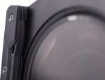 800q-02_108024 Lähikuva Nisi Filter Holder Kit for Laowa 12mm f/2.8 -suodattimen pidikesarjasta kiinnitettynä objektiiviin, jossa näkyy objektiivin lasi, metallikehys ja suodattimen pidikkeen näkyvät ruuvit.