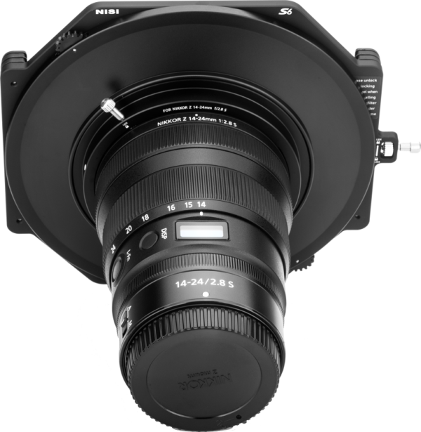 Etunäkymä NiSi-suodattimen pidikkeestä S6 Kit True Color for Nikkor Z 14-24mm f/2.8 S -levysuodin pidike kiinnitettynä kameran objektiiviin, kuvattu vaaleaa taustaa vasten.