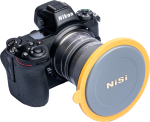 Mustassa Nikon-kamerassa, jossa on suuri objektiivi, on NiSi Lens Cap for V7 Holder, joka on pyöreä, harmaa ja keltainen.