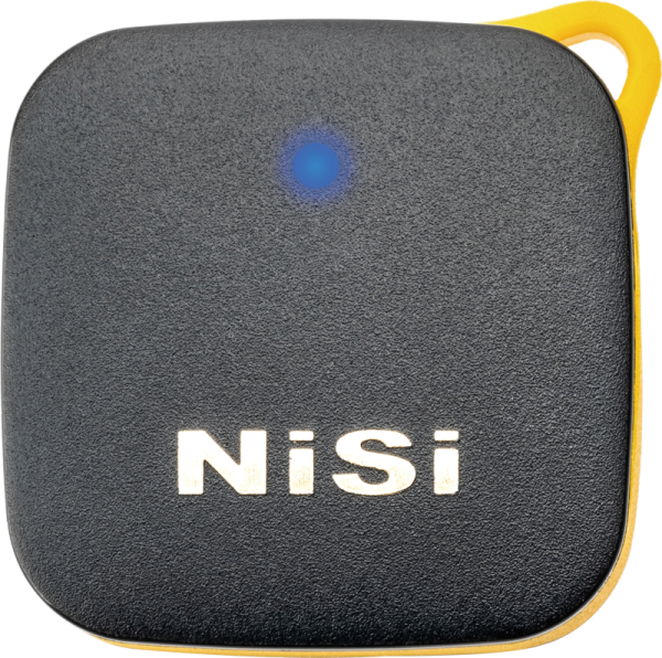 NiSi Remote Control Bluetooth -kaukosäädin on musta, neliönmuotoinen laite, jossa on pyöristetyt kulmat, keltainen reuna, sininen merkkivalo yläreunassa ja valkoinen "NiSi" -merkintä etupuolella.