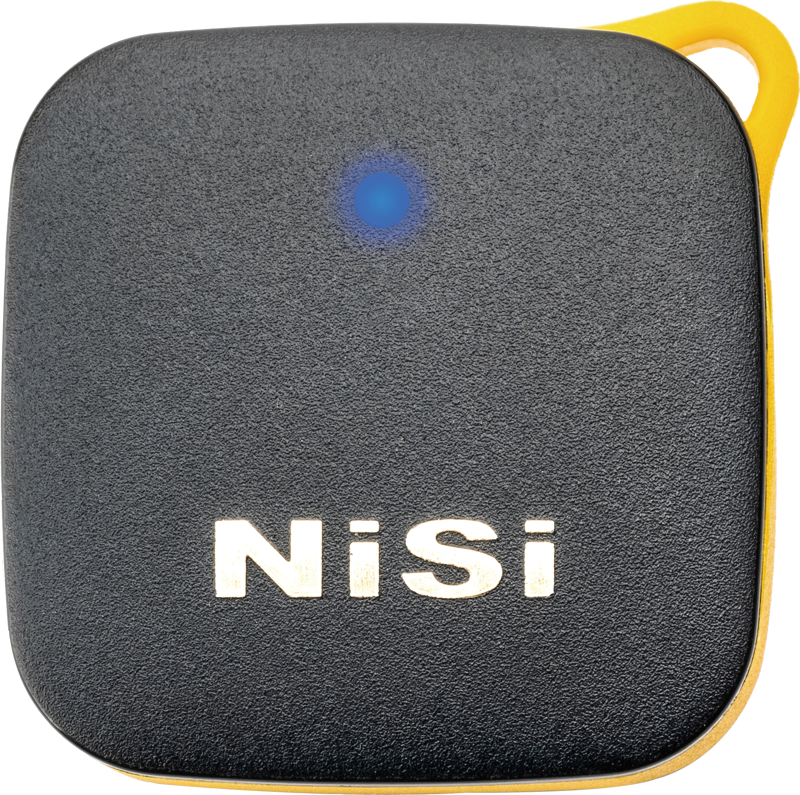 NiSi Remote Control Bluetooth -kaukosäädin on musta, neliönmuotoinen laite, jossa on pyöristetyt kulmat, keltainen reuna, sininen merkkivalo yläreunassa ja valkoinen "NiSi" -merkintä etupuolella.