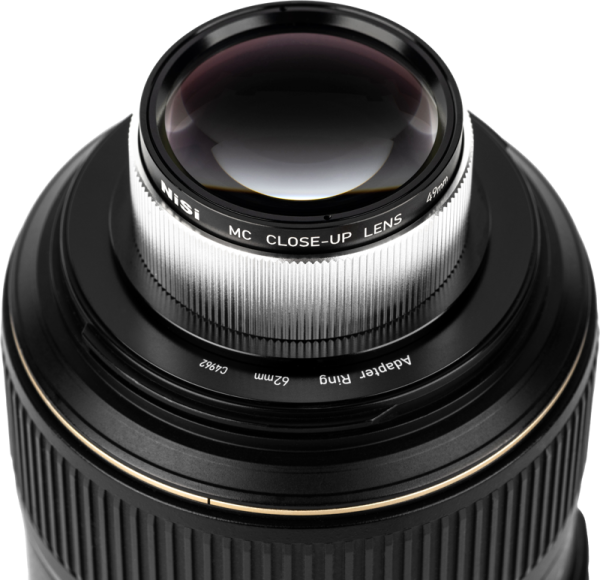 Close-up of a camera lens with a NiSi Close Up Lens Kit NC 49mm close-up lens with detailed grooves and glass elements.