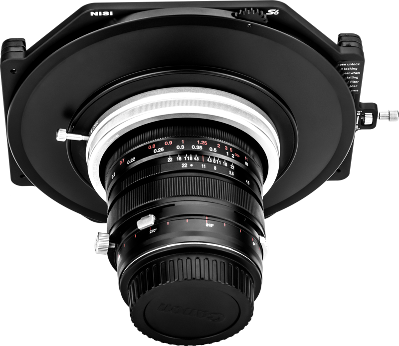 Etukuva mustasta NiSi-suodattimen pidikkeestä S6 Kit Laowa 15mm f/4.5 W-Dreamer -levysuodin pidike asennettuna objektiiviin, jossa on valkoiset merkinnät, valkoista taustaa vasten.