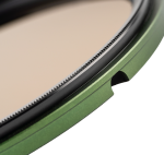 Close-up of the NiSi filter Swift System FS ND Kit (8+64+1000) 40.5-49mm grey filter, showing its green metallic circular shape, brushed black edge and smooth beige surface against a light background.