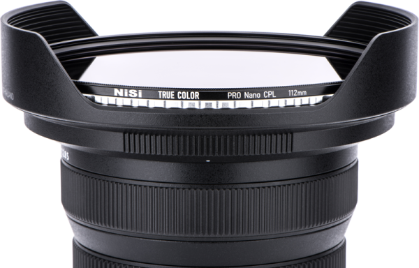 Lähikuva kameran objektiivista, johon on kiinnitetty NiSi Circular True Color Pro Nano CPL 112mm -suodin Nikon Z 14-24mm f/2.8S -pyöröpolarisaatiosuodin, laajakulmalinssin huppu ja kuvioitu tarkennusrengas.