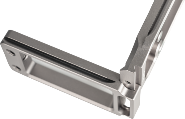 Lähikuva NiSi Universal Adjustable L-Plate NLP-S -levystä, joka on metallinen, L-muotoinen osa, jossa on sileät pinnat, tarkat reunat, kaksi ruuvinreikää toisessa päässä ja kuvioitu ura pitkin sen pituutta.