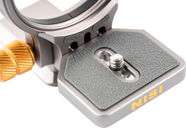 Lähikuva NiSi Wizard Camera Positioning Bracket W-63 -metallikiinnikkeestä, jossa on kuvioitu harmaa pikakiinnityslevy ja hopeinen jalustaruuvi, jota korostavat kultaiset ja hopeiset korostukset.