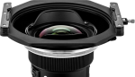 Lähikuva NiSi-suodattimen pidikkeestä S6 Alpha Kit for Sigma 14mm f/1.4 DG DN -levysuodin pidike, jossa on suuri kaareva lasielementti ja suorakulmainen huppu valkoista taustaa vasten.