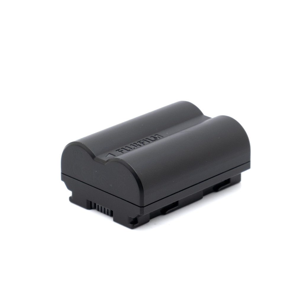 The used Fujifilm NP-W235 (incl.ALV24%) black rechargeable camera battery rests on a white base, with its curved top and bottom connectors visible.