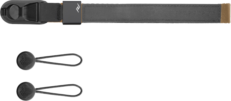 Peak Design Cuff Wrist Strap with coyote coloured buckle and two round black anchor fasteners with loops arranged on a light background.