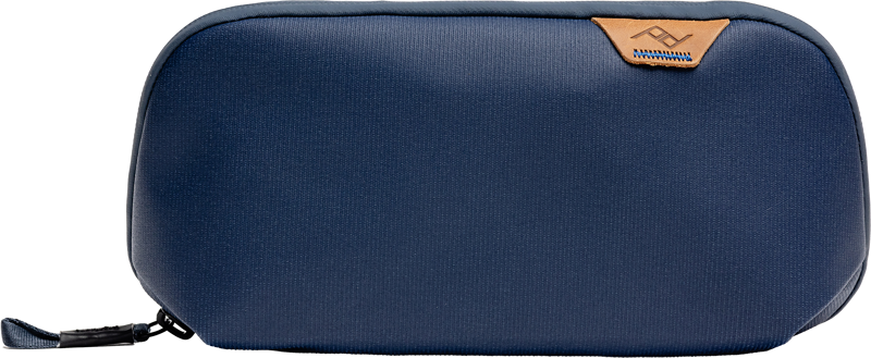 The Peak Design Tech Pouch Small - Midnight is a navy blue pouch with a black zipper pull and subtle brown leather accents against a white background.